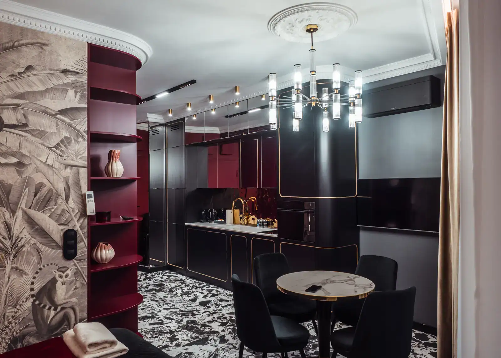 Cool designer apartment in Gdansk, with burgundy and black cabinetry with gold details, black and white patterned floor, modern chandelier hanging from a rosette. One of the most beautiful apartments in Gdansk.