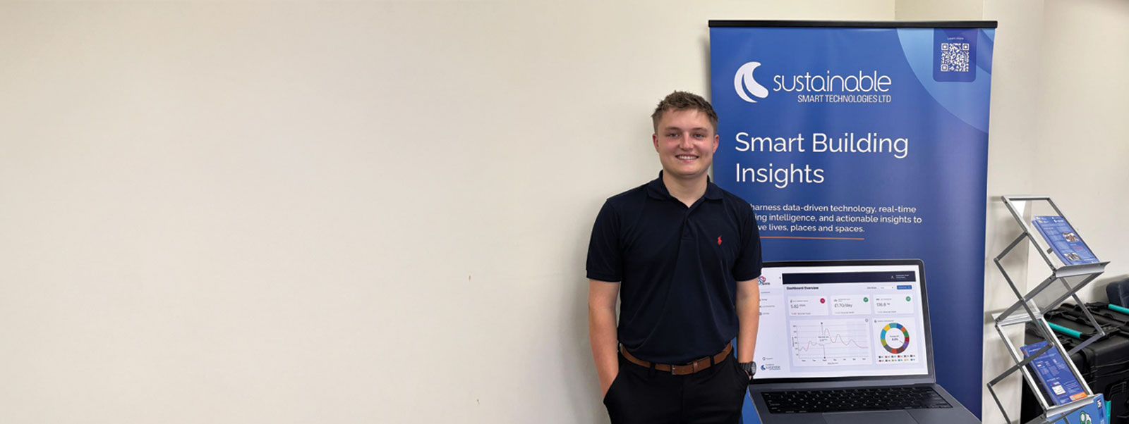Archie Miller, new junior sales executive, flanked by SST banner stand: "Smart Building Insights".