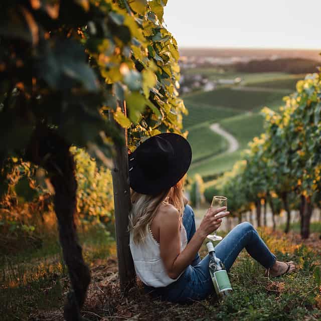 young-blonde-woman-relaxing-vineyards-summer-season-with-bottle-wine