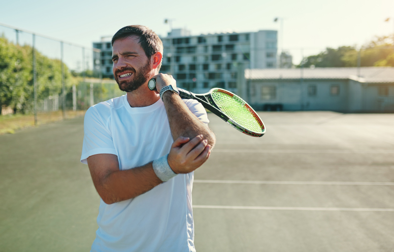 Tennisspiller holder sin albue i smerte, søger øjeblikkelig hjælp til lindring og behandling.