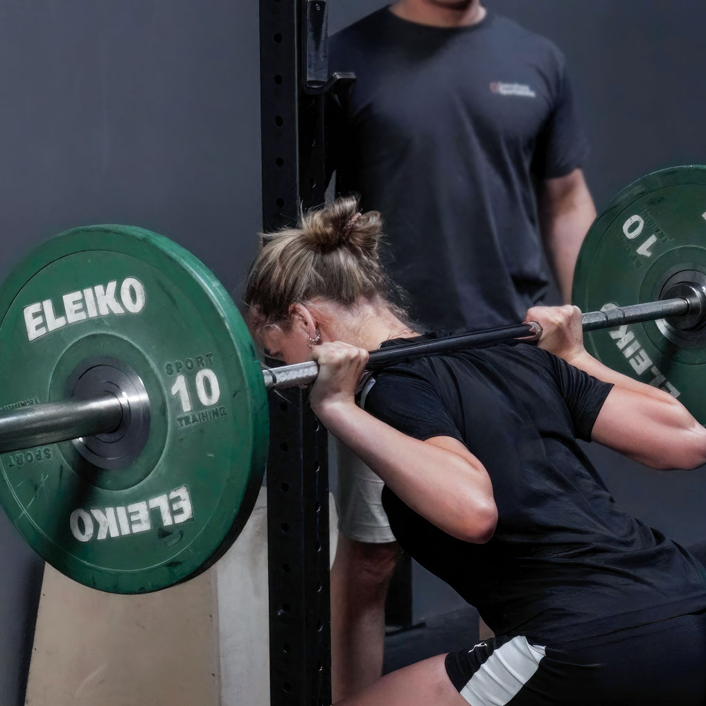 En kvinde, der udfører vægtløftning under en rehabiliterings- og træningssession på et sportscenter