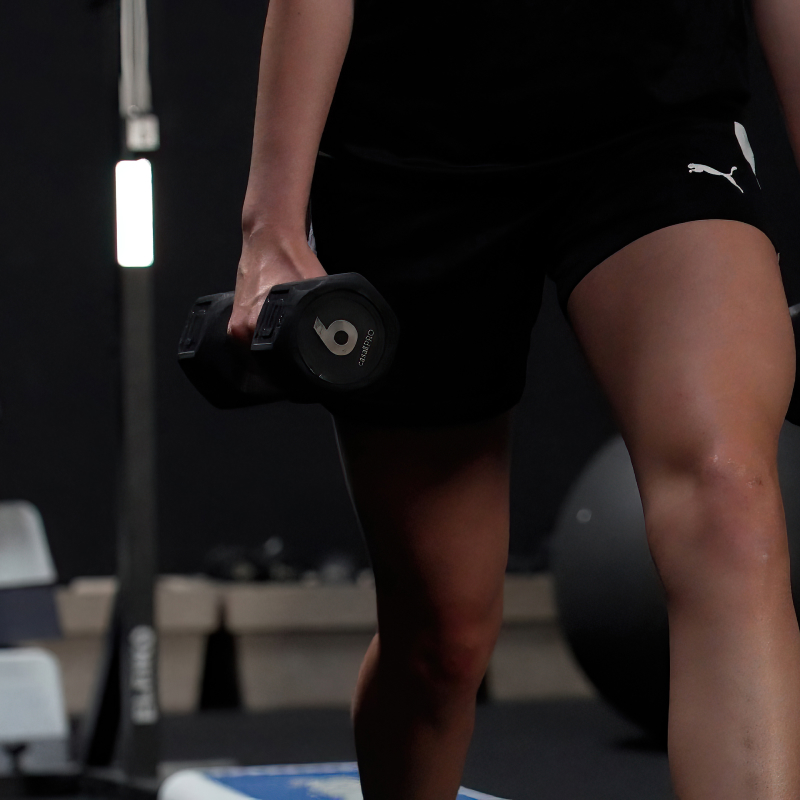 Billede af en kvinde, der udfører styrketræningsøvelser med vægte på sportsklinikken