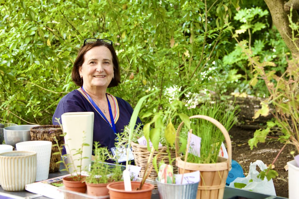Secretary Tracey in amongst shrubs on the plant stall.