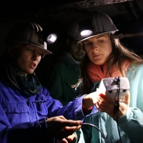 Women wearing hard hats and a light on a device