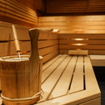 A picture of a sauna in Sweden, a traditional place where people relax and sweat in a hot and steamy room. The sauna is made of wood and has a stove with hot stones that create the heat. There is a bucket to pour water to make steam.