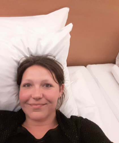 Laying on a hotel bed with white sheets.