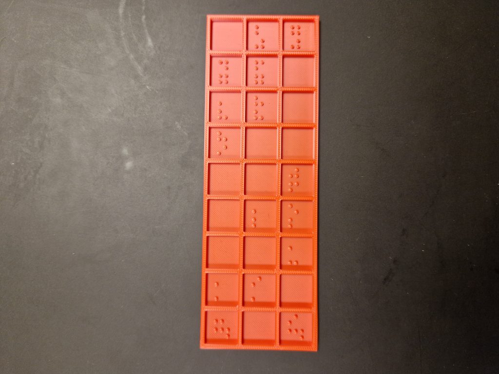 Red Bingo card with raised Braille numbers arranged in a 3 by 9 grid Taktil Innovation Aps