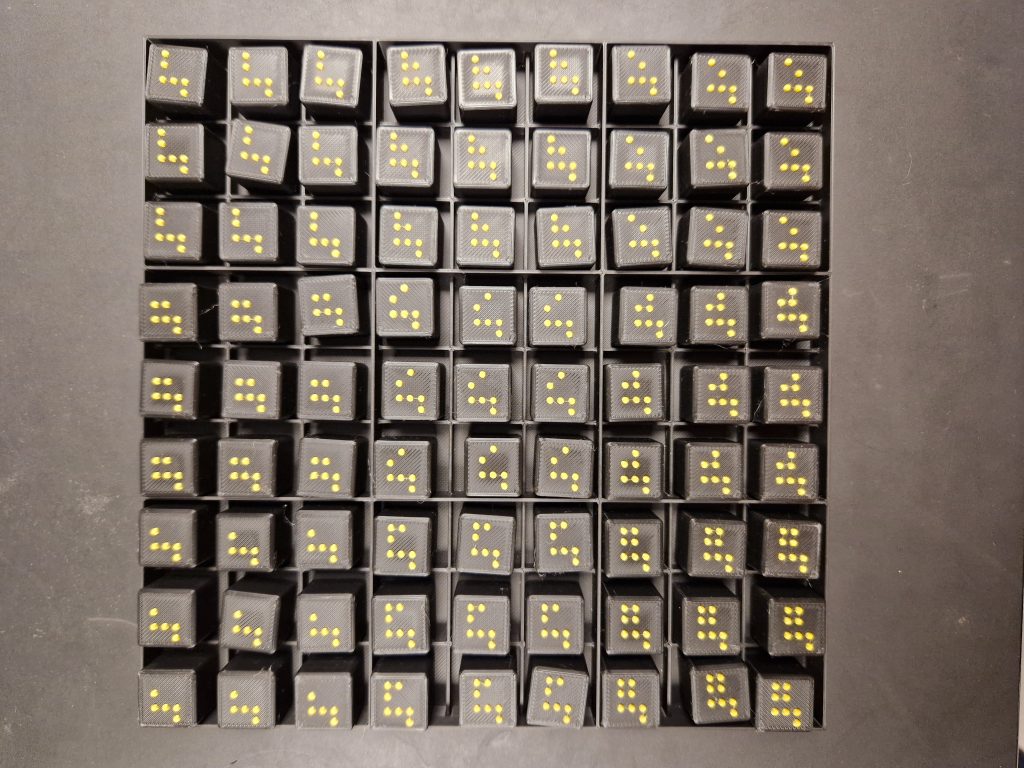 Black Sudoku board with raised yellow dot patterns in each square, arranged in a 9 by 9 grid at Taktil Innovation Aps