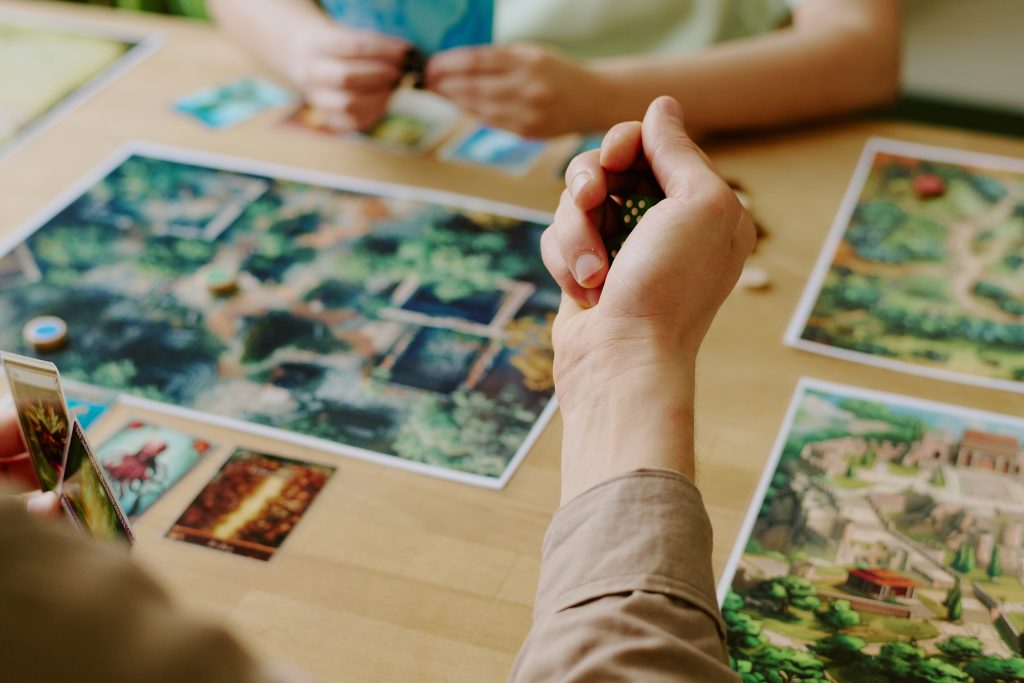People playing a strategy board game with cards and dice