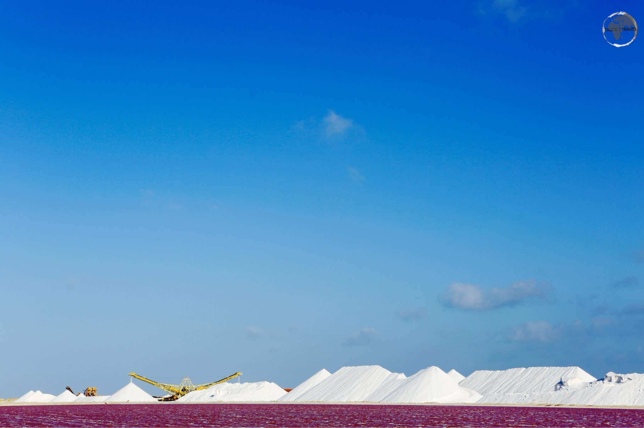 The purple briny water of a salt-water pond contrasts against the mounds of white salt at the Cargill Salt Mine.