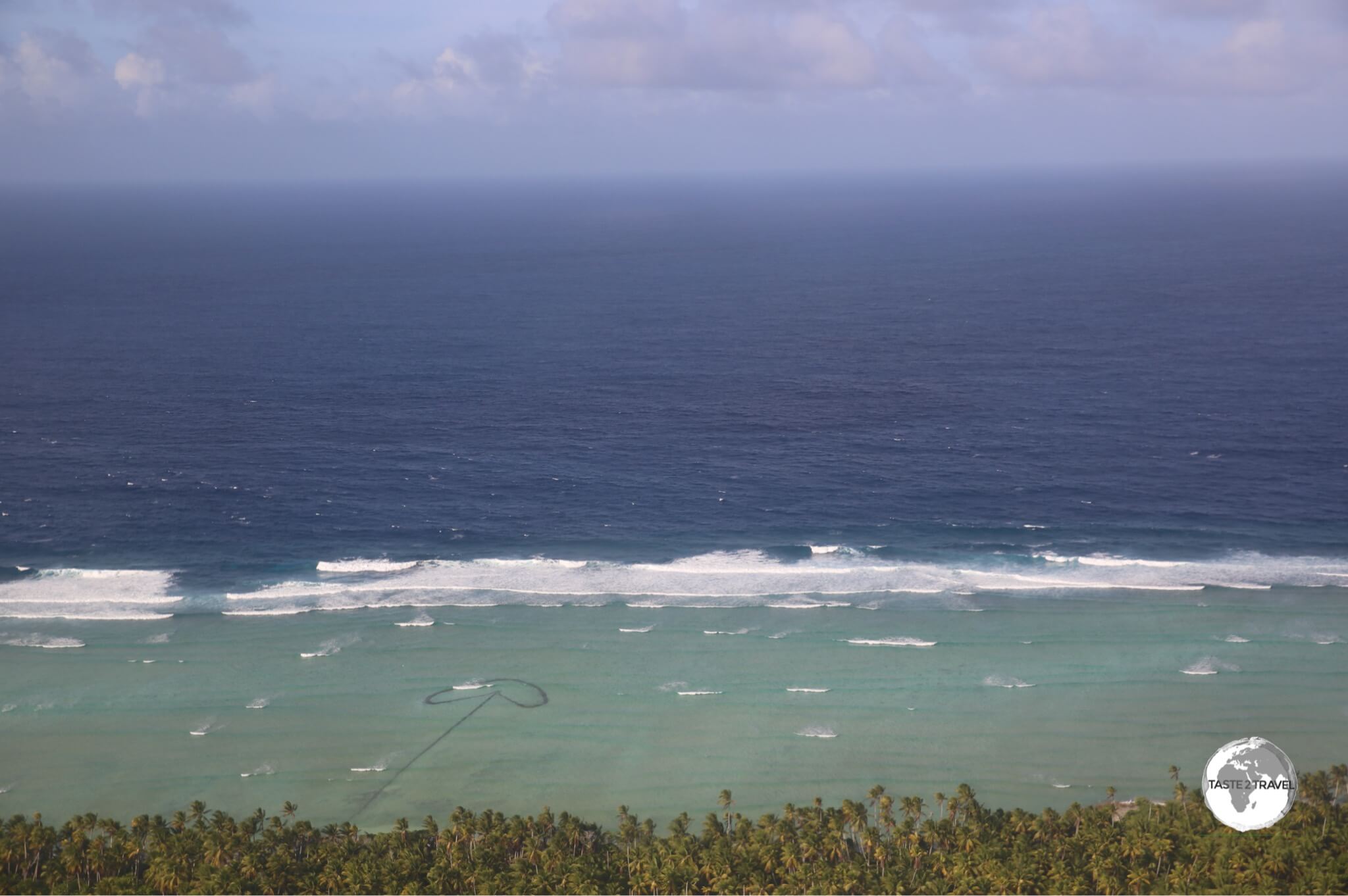 A view of Maiana Island with a stone fish trap visible below the shoreline.