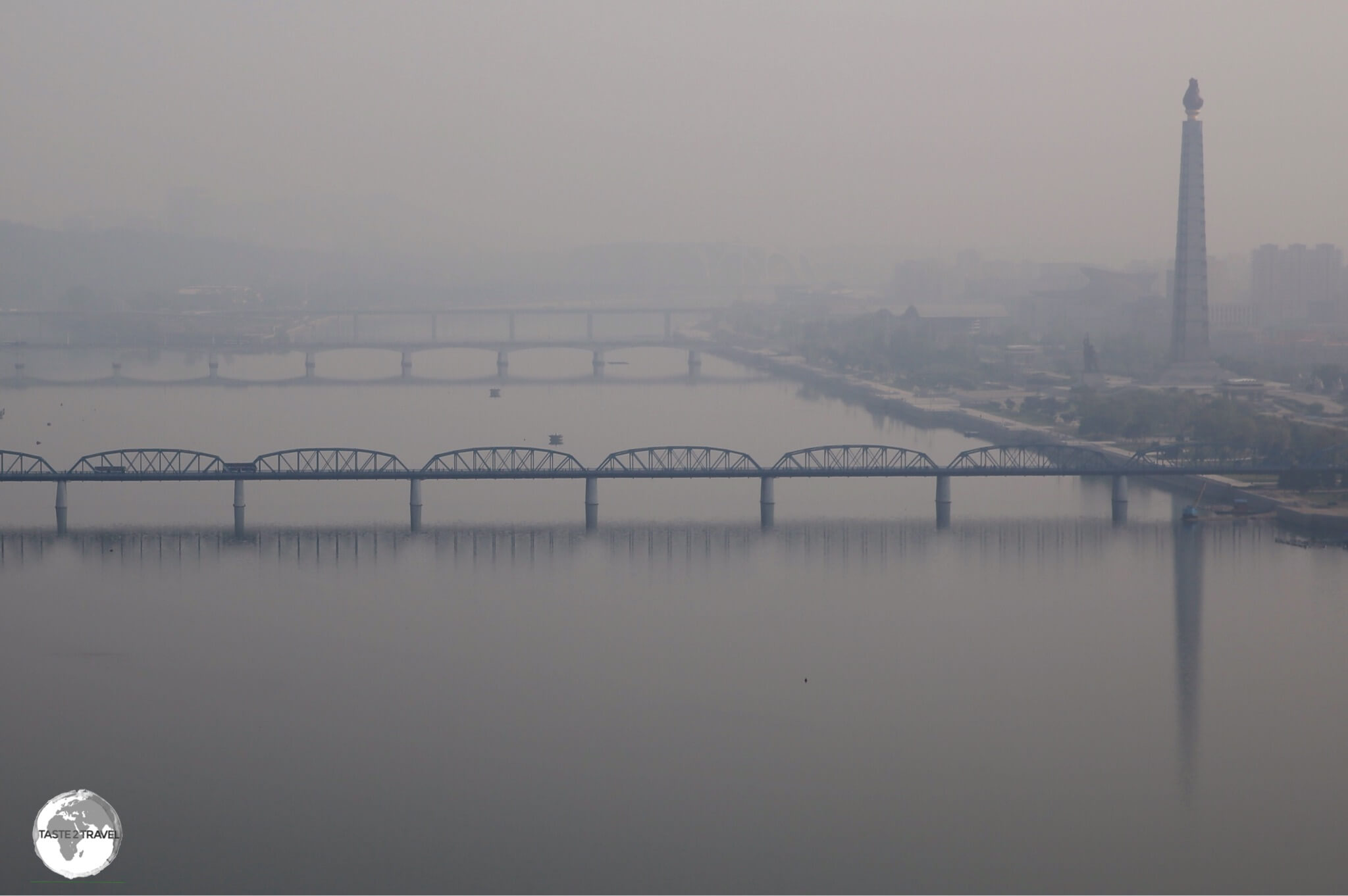 An early morning view, from my hotel room, of the Taedong River in Pyongyang, with the <i>Juche Tower</i> standing sentinel on the right bank.