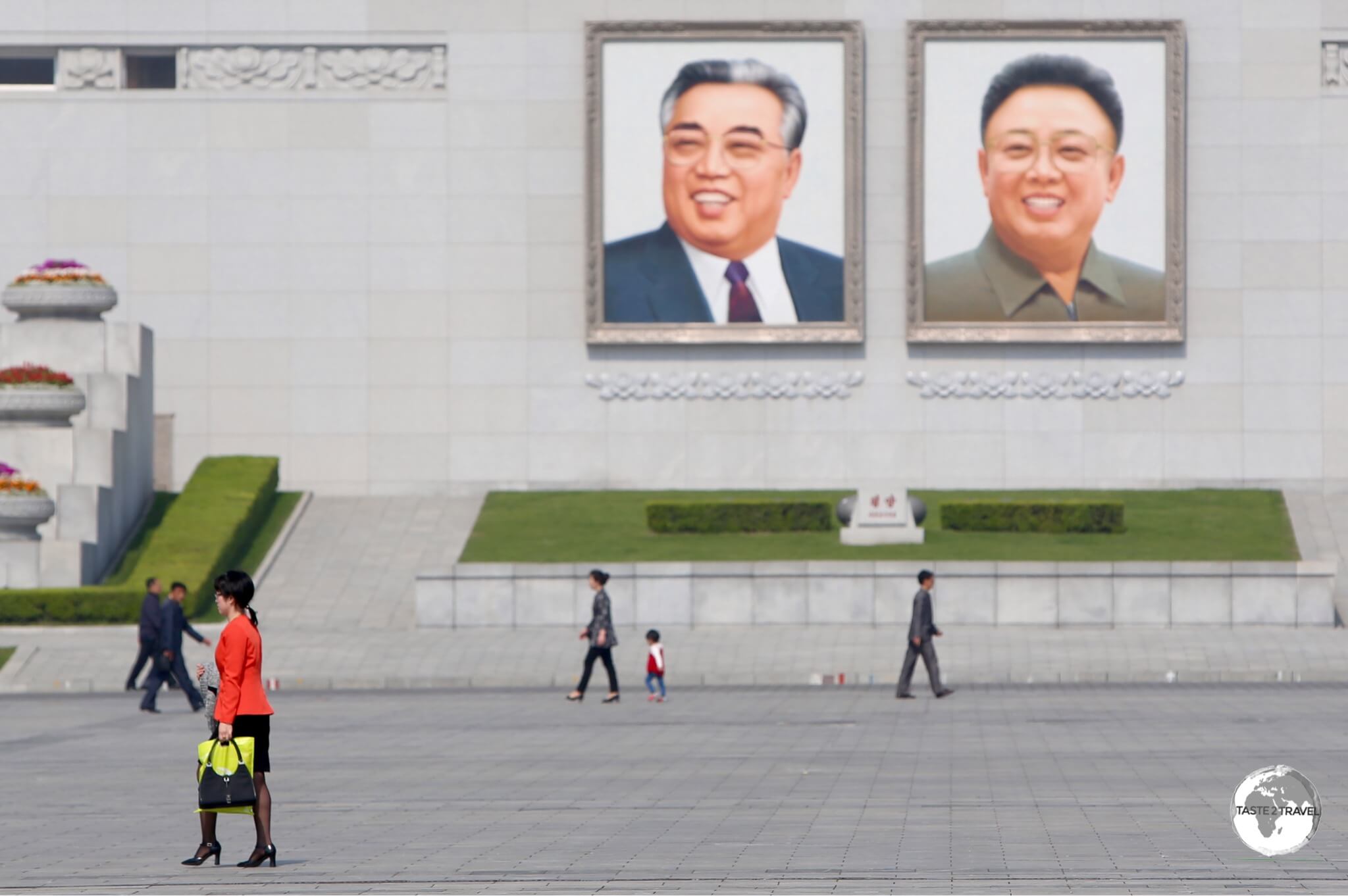 A cyclist passes in front of images of the former leaders, Kim Il-Sung and Kim Jong-Il which overlook Kim Il-Sung square.