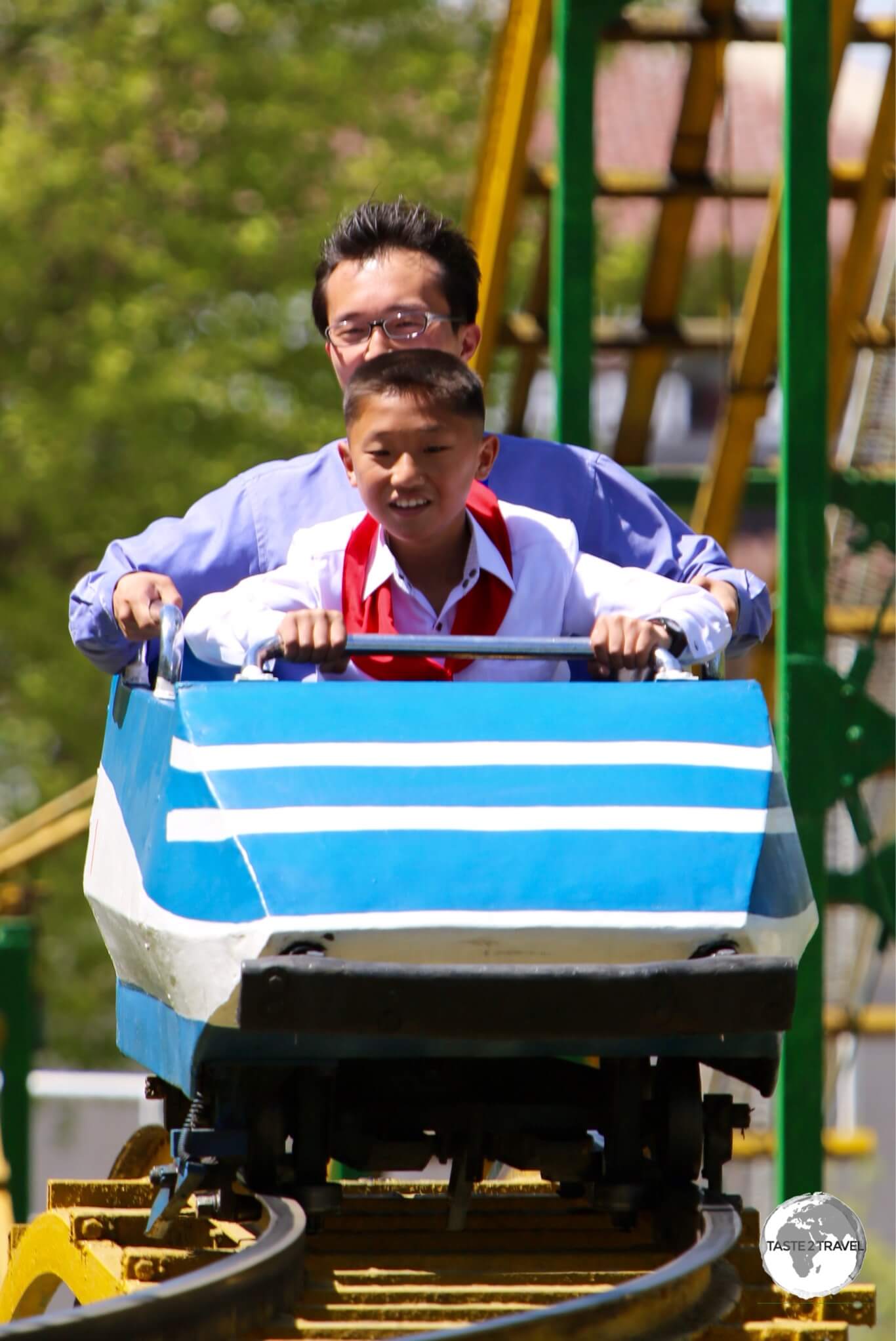 A father and son enjoying a roller coaster ride at Taesongsan Fun Fair on a busy May day public holiday.