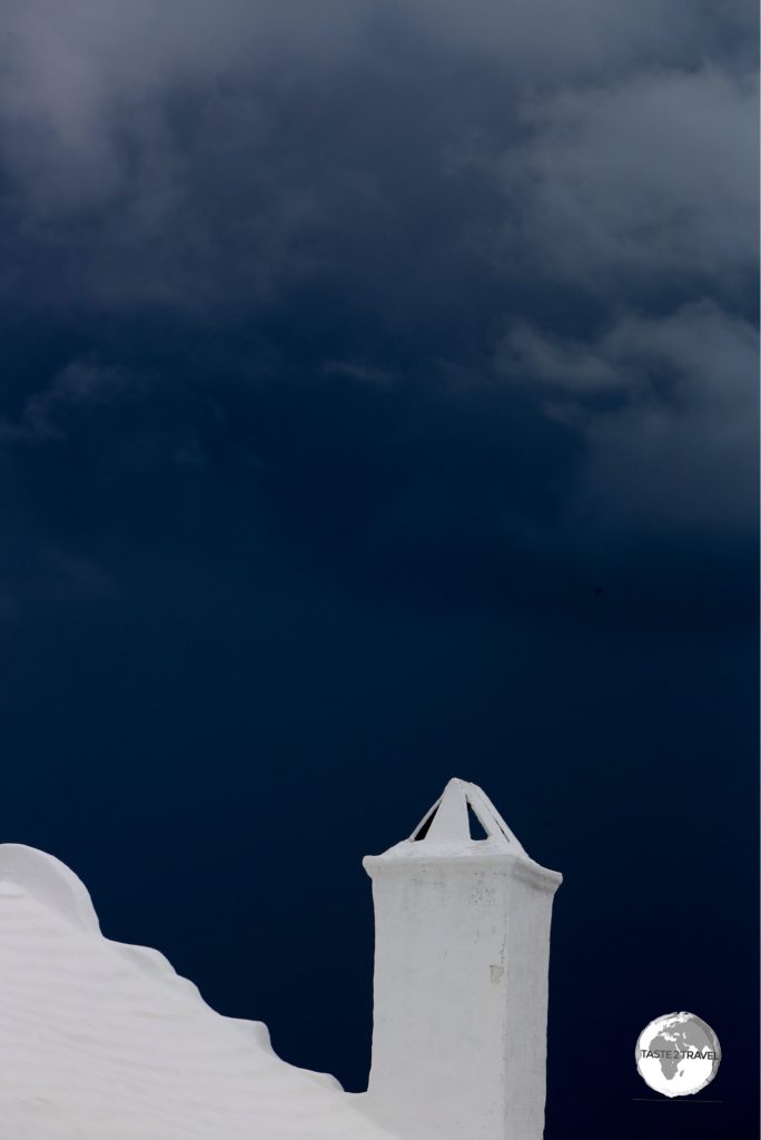A white-painted, stone roof contrasts starkly against a stormy sky.