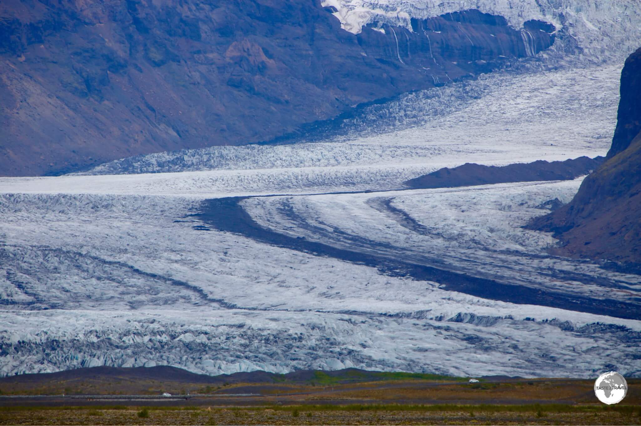 Cars passing in front of Skaftafellsjökull provide a sense of scale.