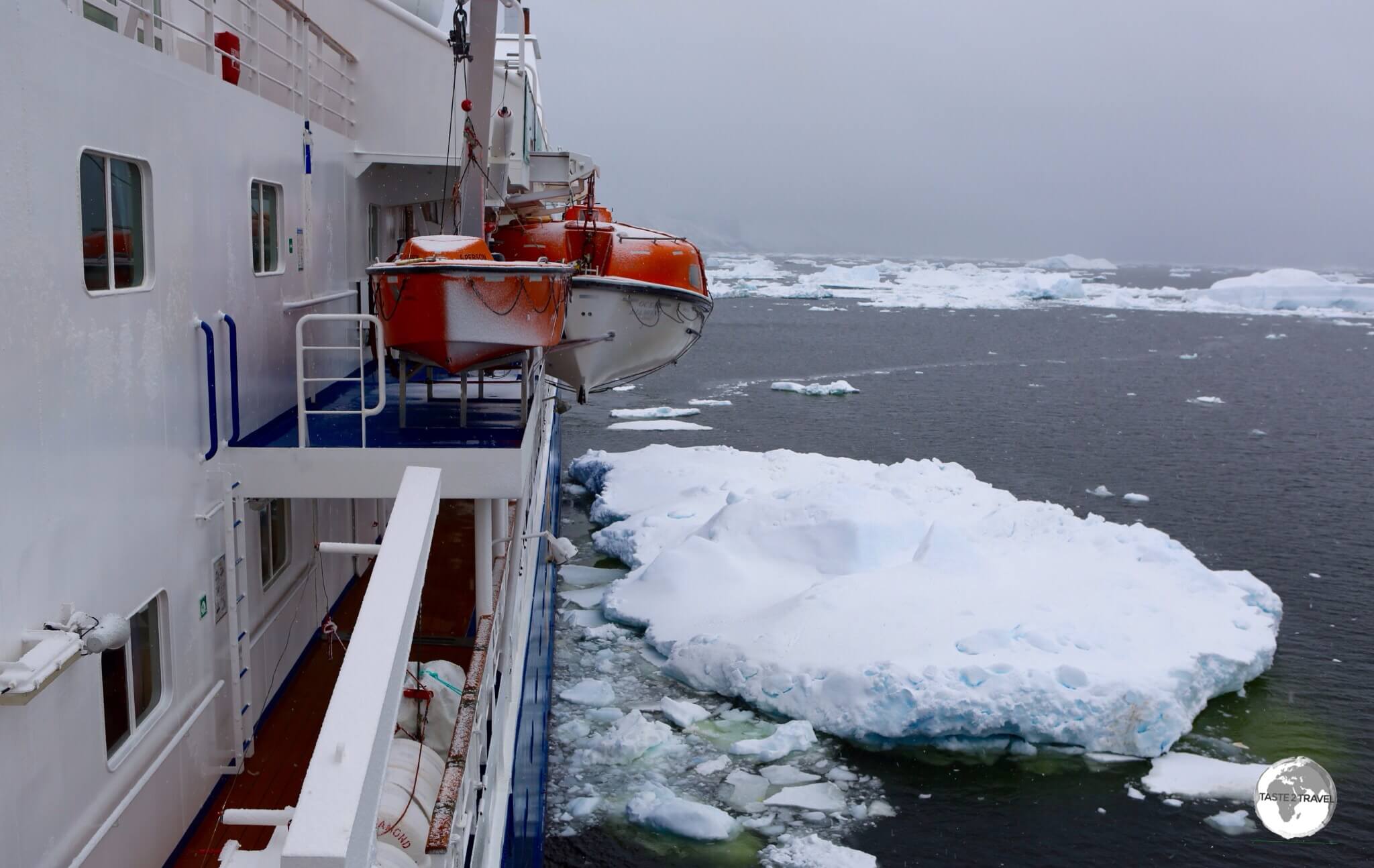 The <i>Ocean Diamond</i>, moored against a large chunk of ice, on a stormy day, in the Yalour Islands.