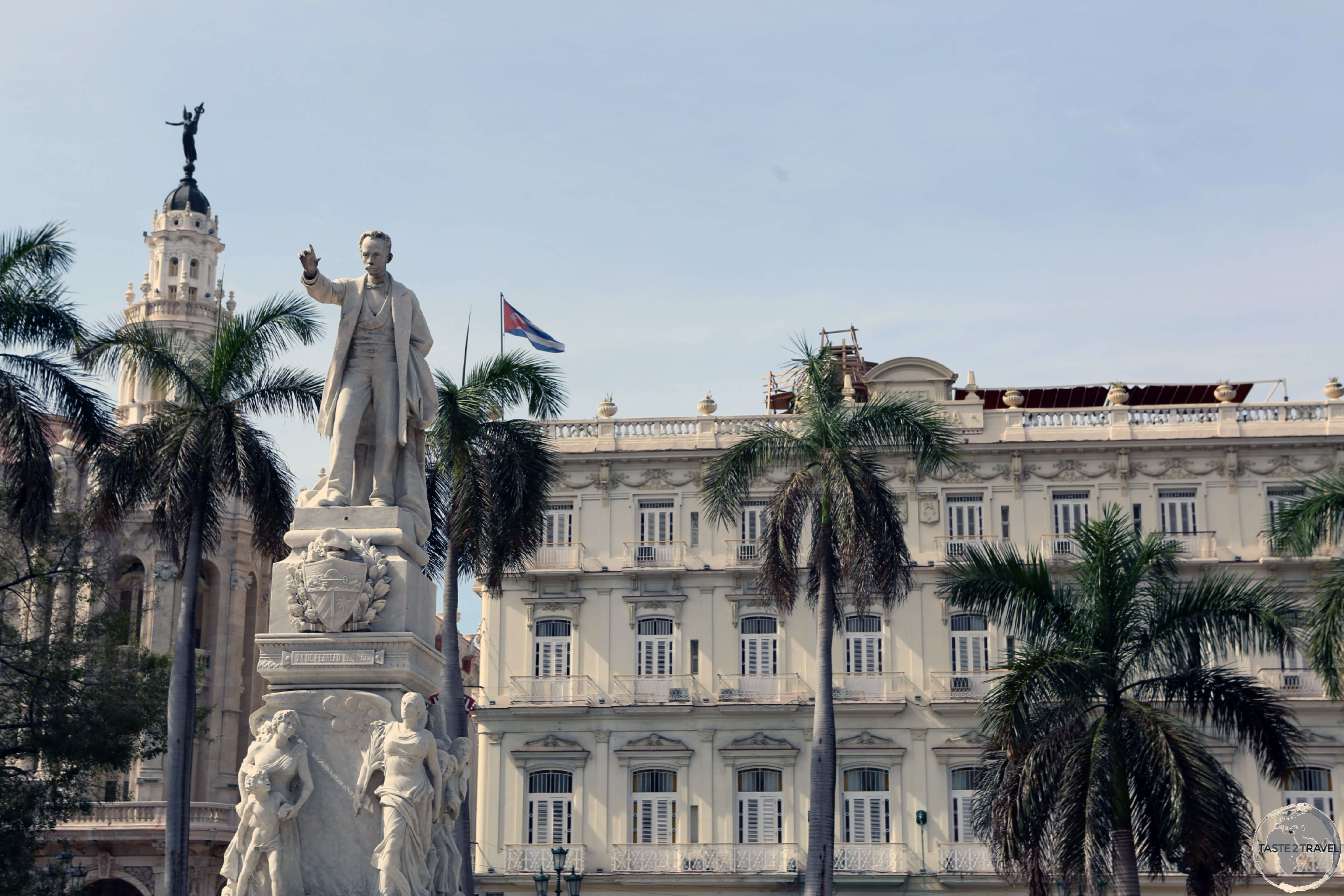 A statue of José Martí in Central Park with the <i>Hotel Inglaterra</i> in the background.