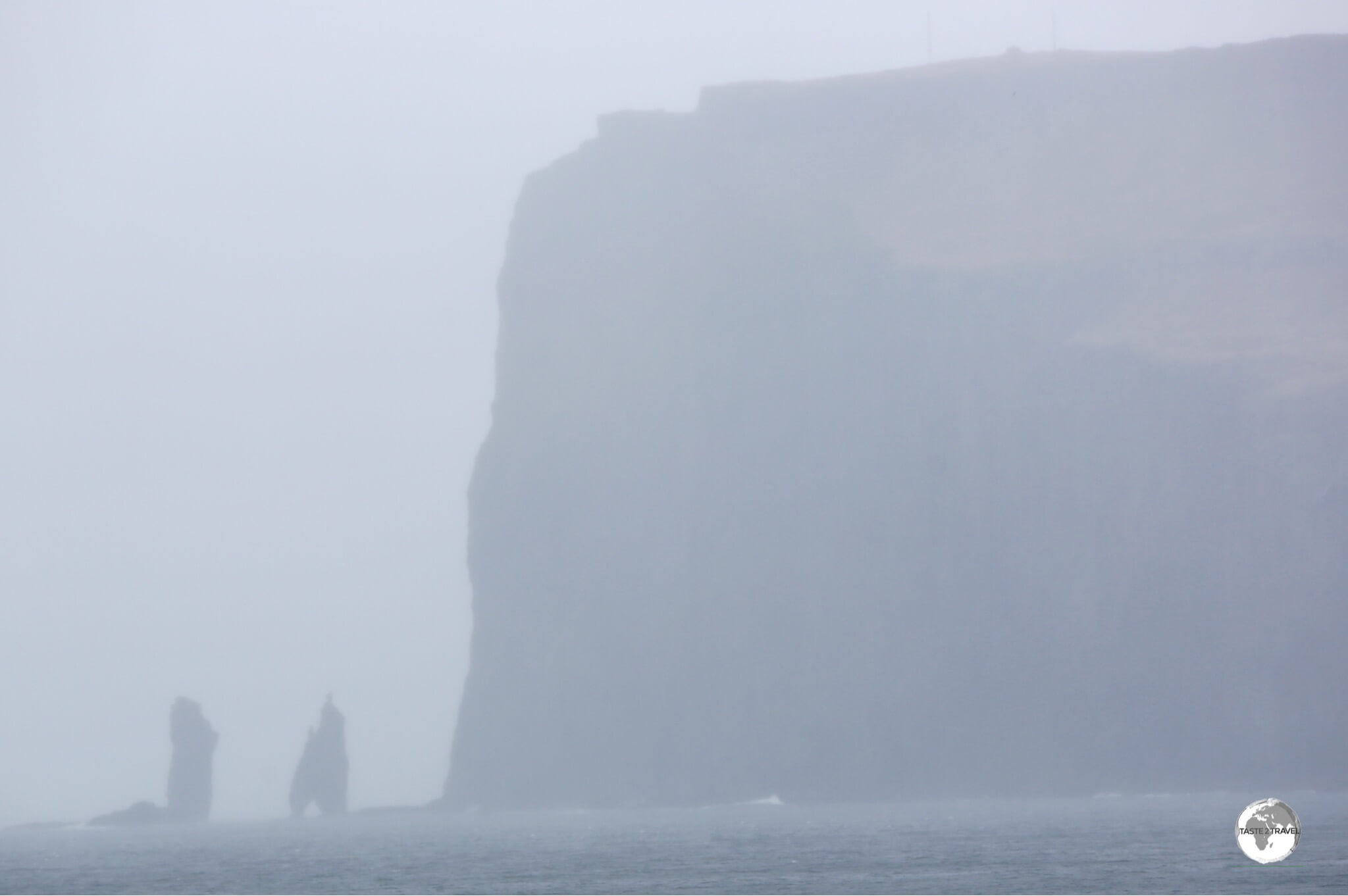 A hazy view of the soaring 343-metre-high Eiðiskollur promontory with the two 75-m high sea stacks - Risin og Kellingin.