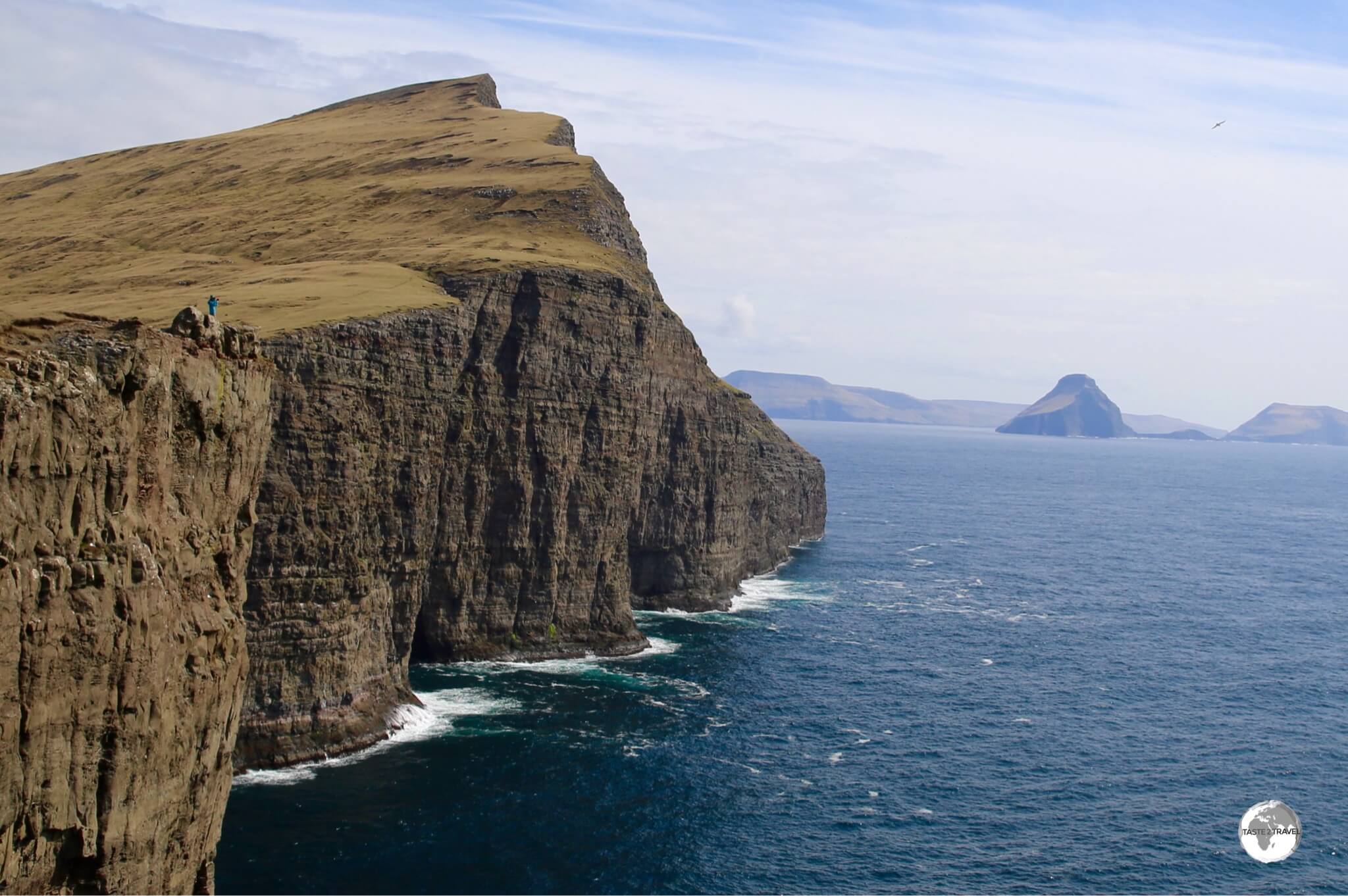 A lone hiker lends a sense of scale to the magnificent scenery on the coast of Vágar island.