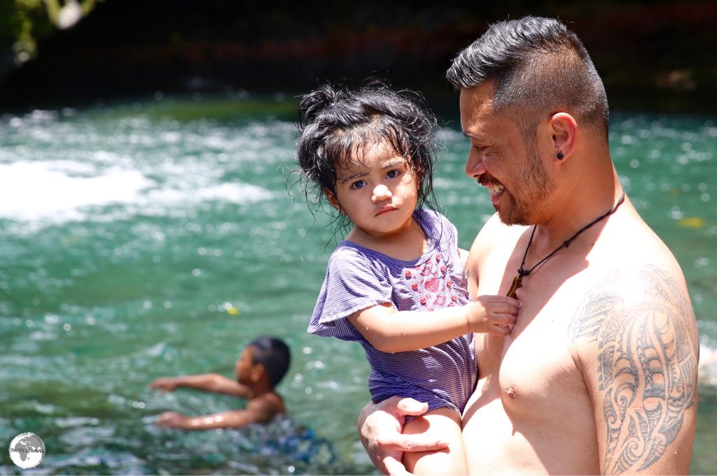 A Samoan family enjoying a swim at the Togitogiga Waterfalls.