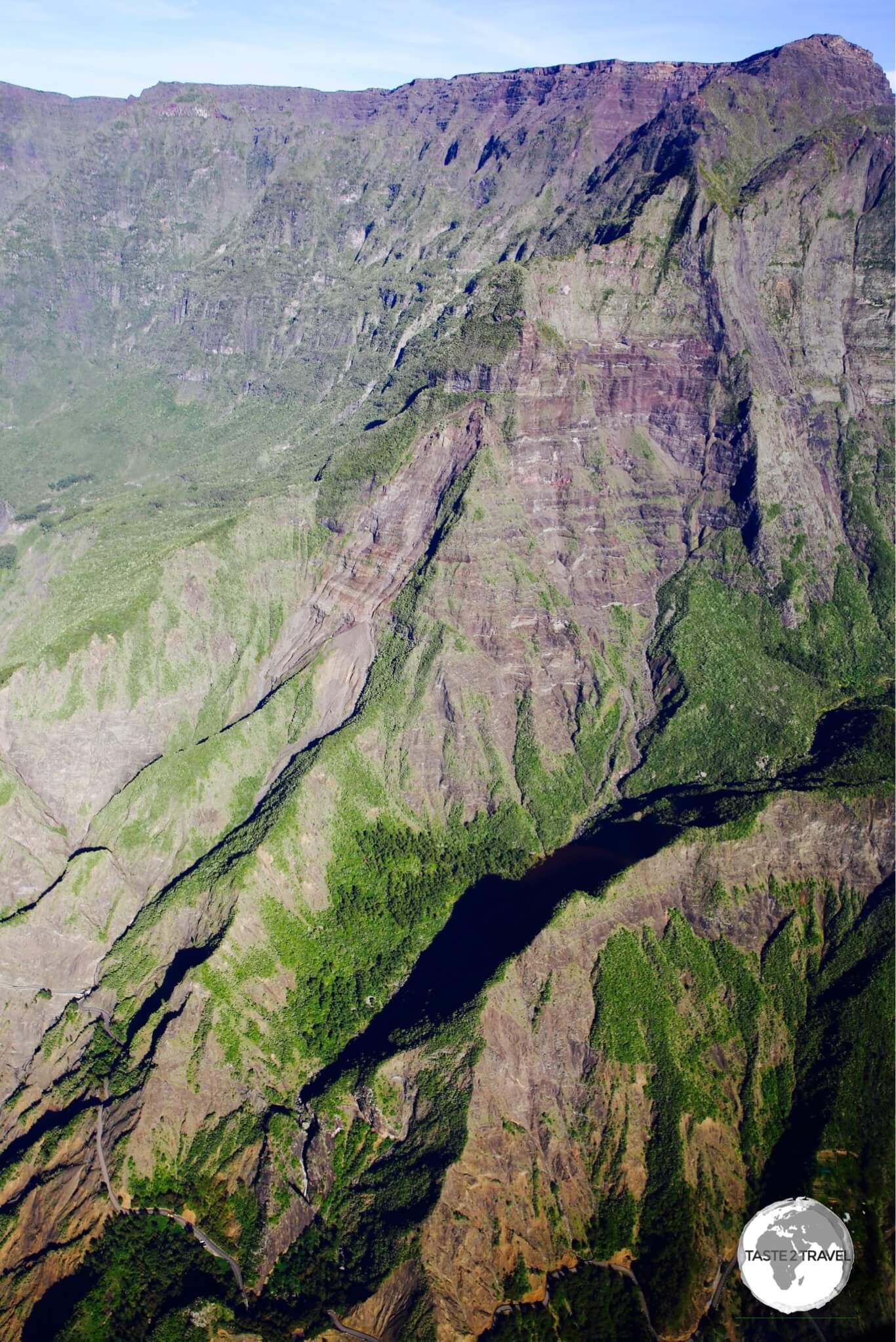 As seen from a helicopter, the narrow, windy road (bottom left corner) which passes beneath the vertical walls of the Cirque de Cilaos, providing access to the tiny hamlet of <i>Îlet à Cordes</i>.