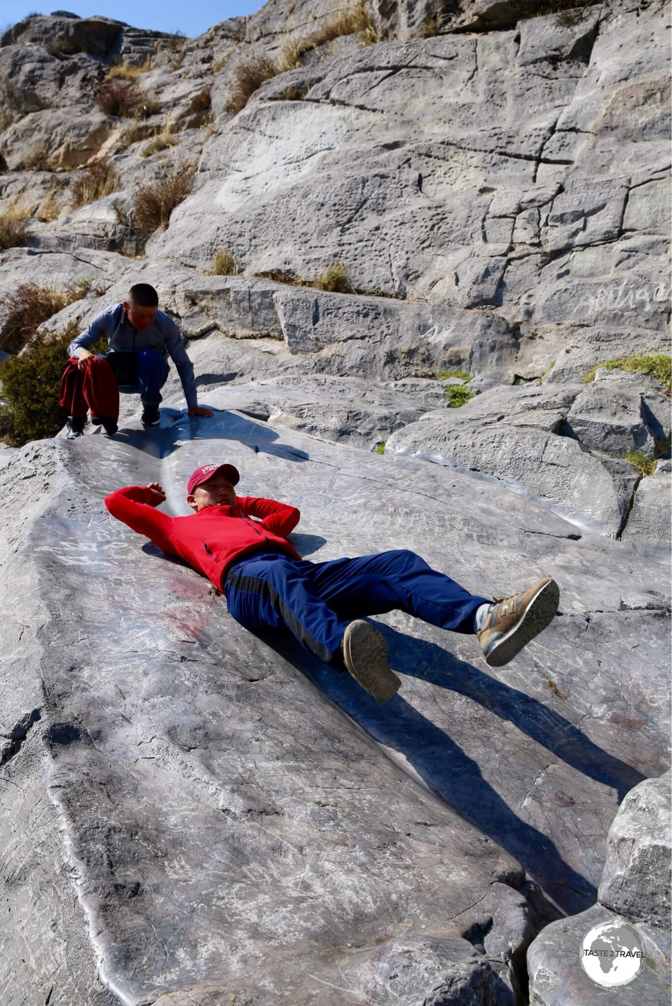 Locals sliding down the smooth, polished, limestone rock on Sulaiman-Too mountain.