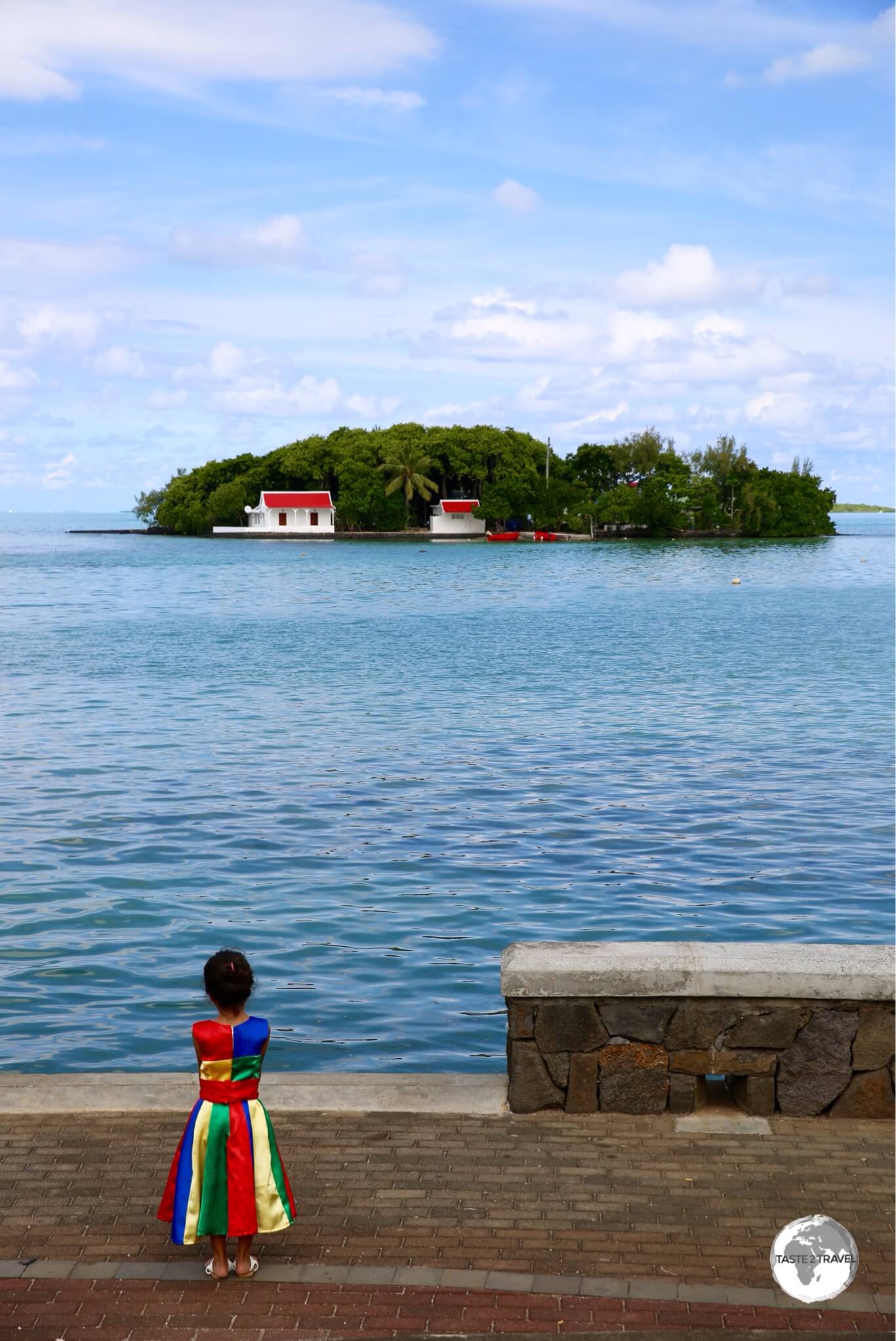 A young girl at Mahébourg, wearing the Mauritius national colours, with the island of Mouchoir Rouge in the background. 