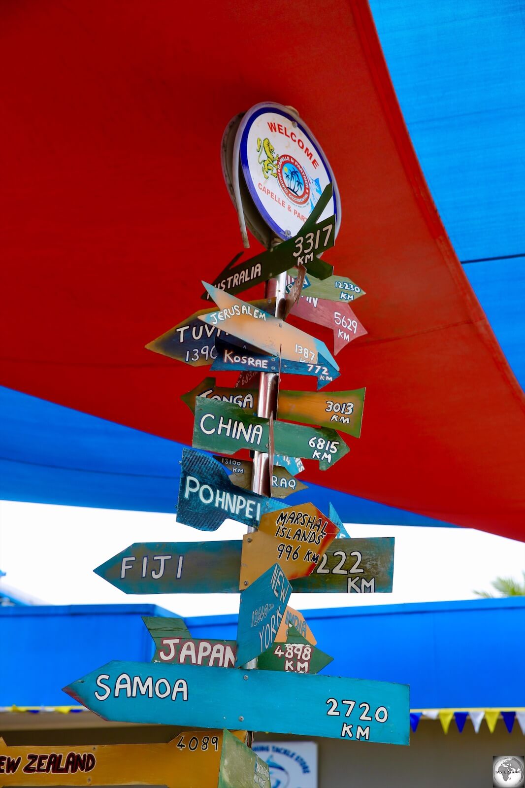 A signboard outside of the Capelle and Partner supermarket indicates distances to different countries from Nauru.