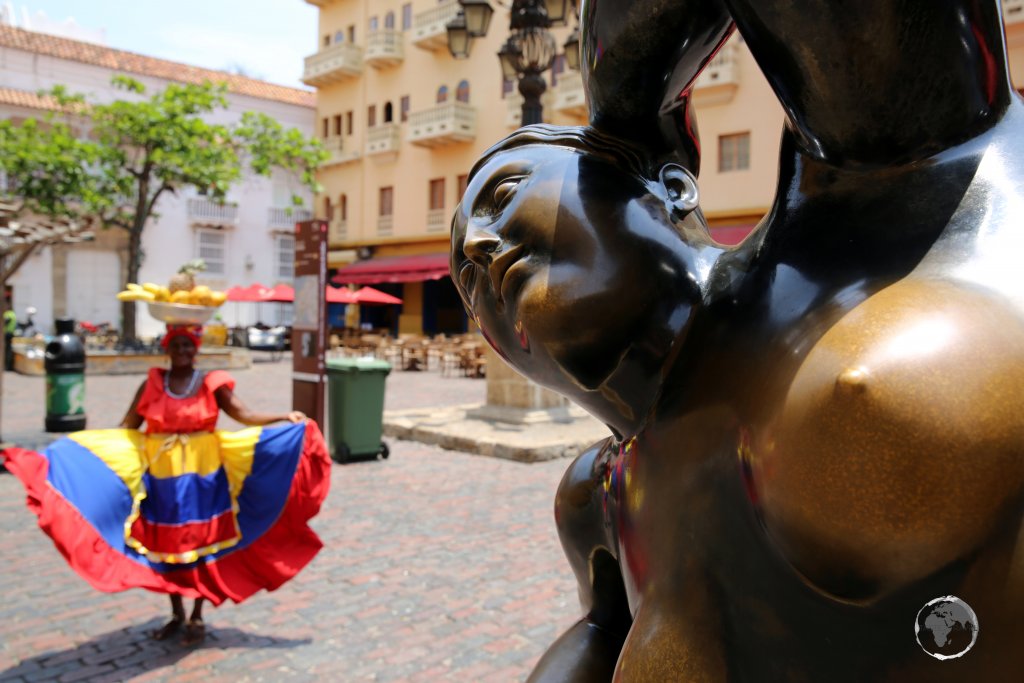 A colourful fruit seller, known as a 'Palenquera', poses behind Fernando Botero’s reclining nude, 'La Gorda Gertrudis' (Fat Gertrude) in Plaza Santo Domingo, Cartagena.