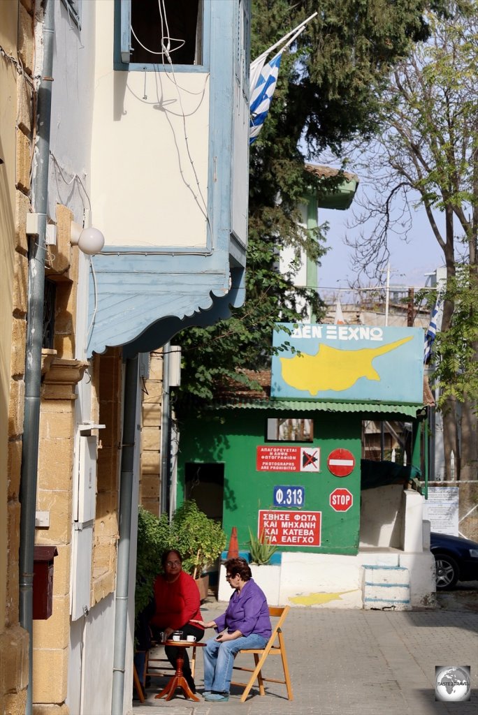 Residents on the Greek side of the UN Green Line sit and chat in front of a section of wall.