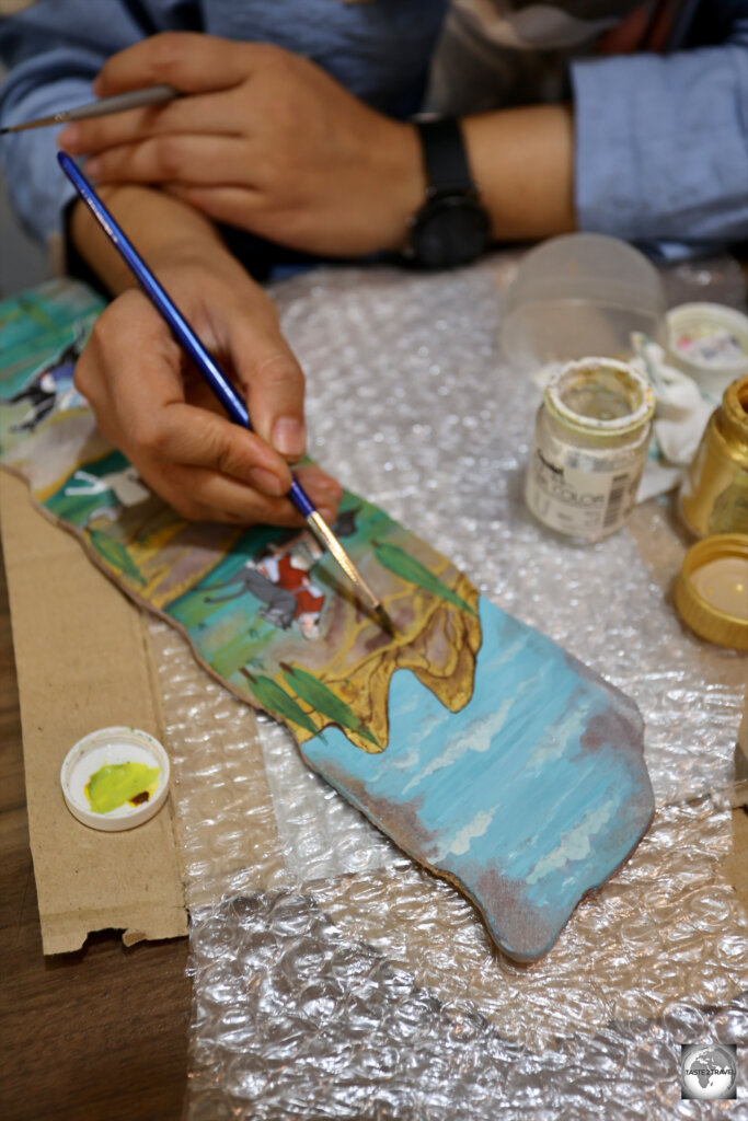 An artist at Qavam House, painting a miniature on a piece of stone.