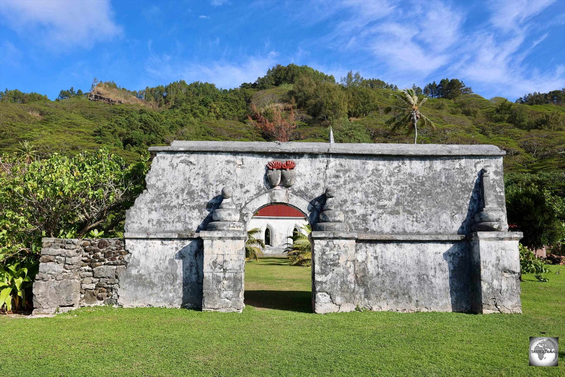 A fragment of an old wall on Taravai Island, which offers a view of the Church of Saint-Gabriel and the twin hearts of Les Sacrés-Coeurs de Picpus.