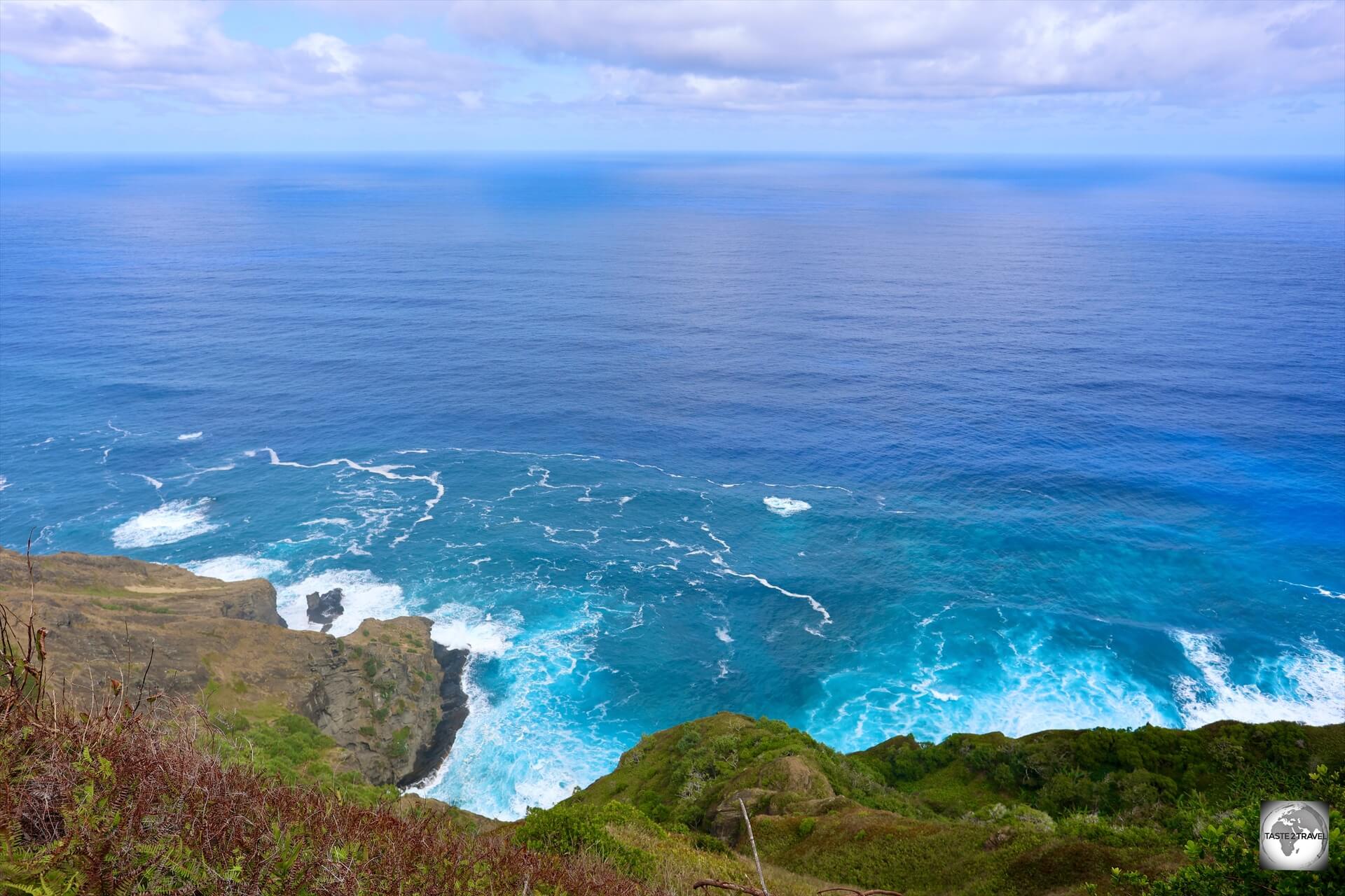 A volcanic island, Pitcairn is surrounded by the deep waters of the Pacific Ocean, with waves pounding against high coastal cliffs.