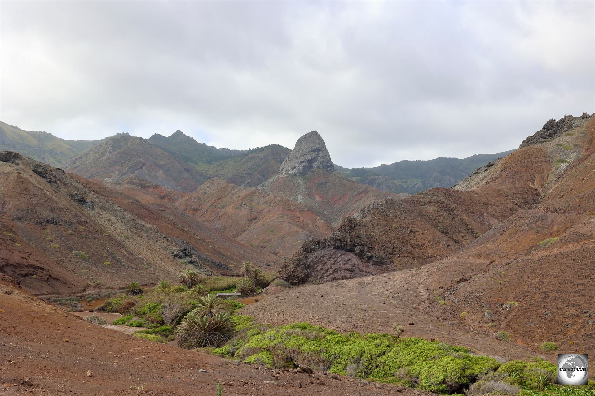 A view of the arid coastal landscape at Sandy Bay with the volcanic formation, 'Lot', in the background.