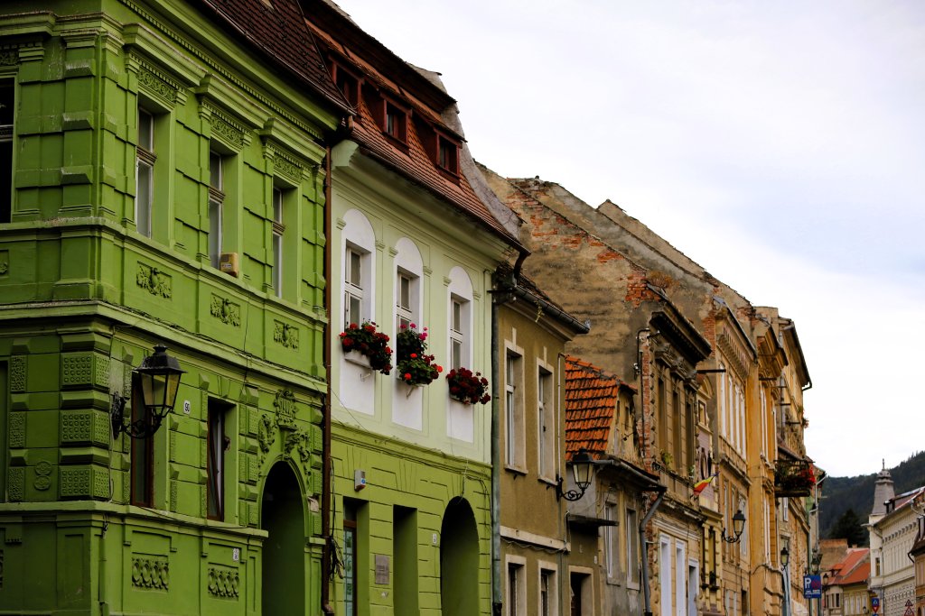 Brașov old town has cobblestone streets, red-roofed buildings, and partially-walled sections.