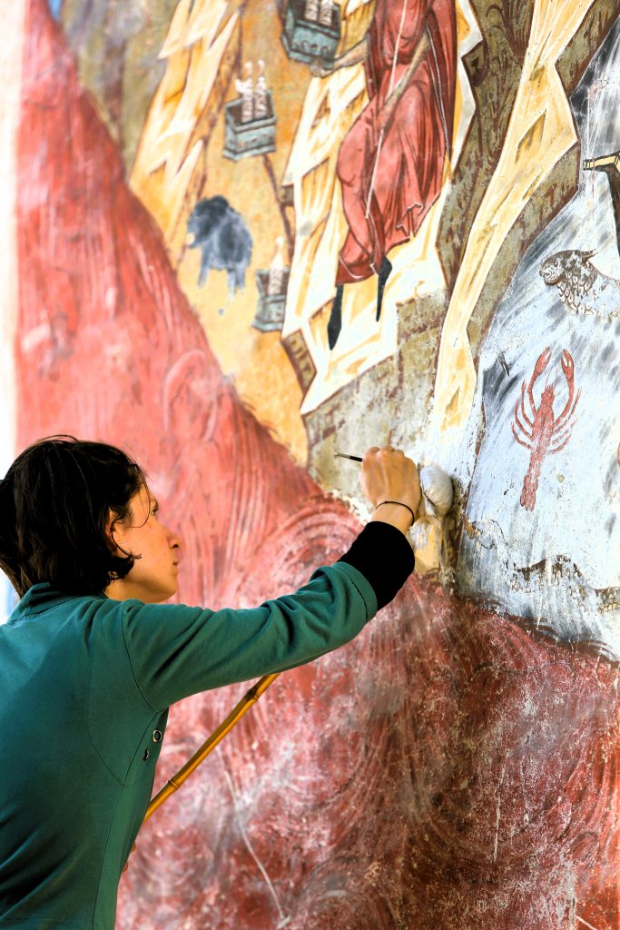 An artisan, restoring a frescoe, at Humorului Monastery.