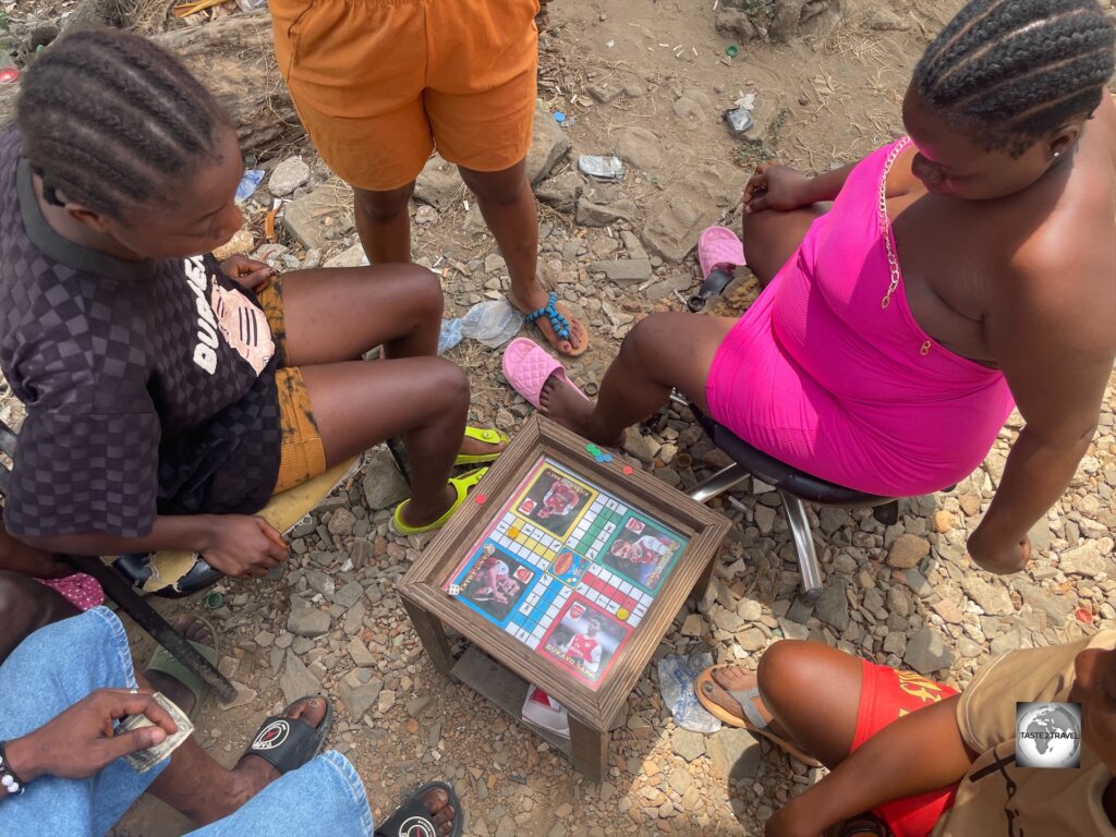 Locals in Monrovia, gambling on the popular boardgame - "African Delights' Ludu Board Game" which features African cultural figures.