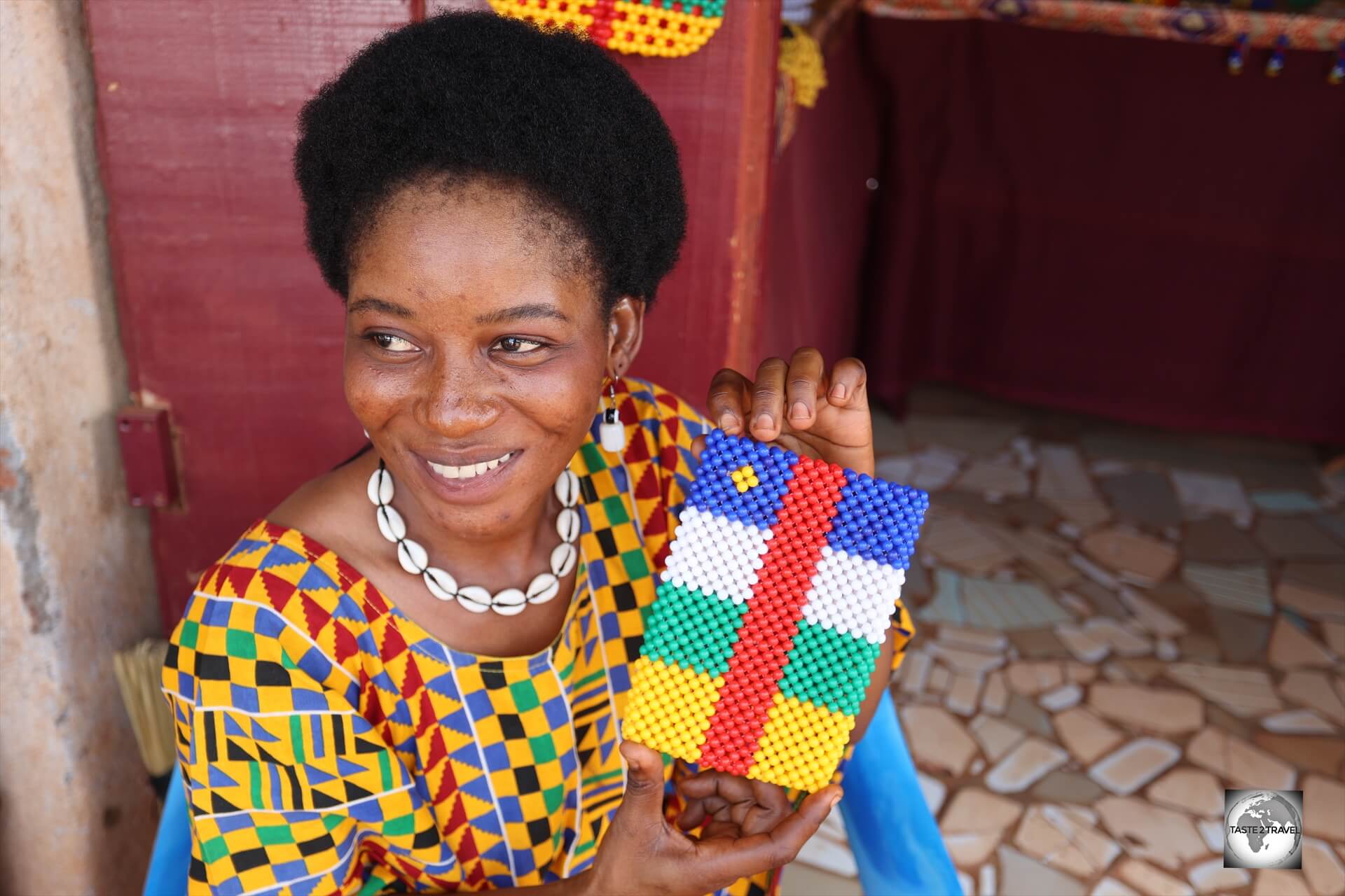 A craft shop owner in Bangui, displaying a CAR flag-themed mobile phone beaded carrier.
