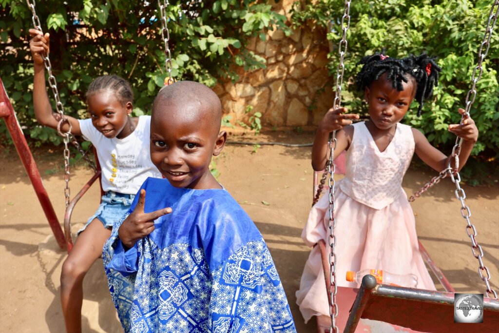 Children, playing on a swing set, in the garden of the Maison Russe in Bangui.