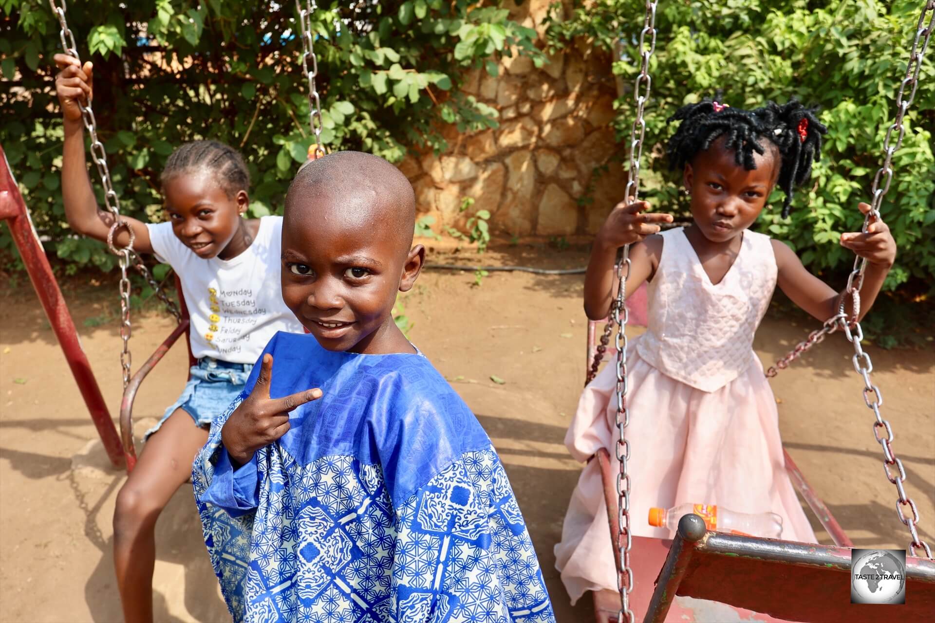 Children, playing on a swing set, in the garden of the Maison Russe in Bangui.