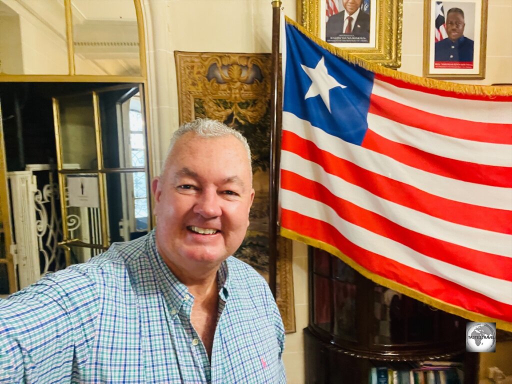 Posing, with the flag of Liberia, at the Liberian embassy in Paris.