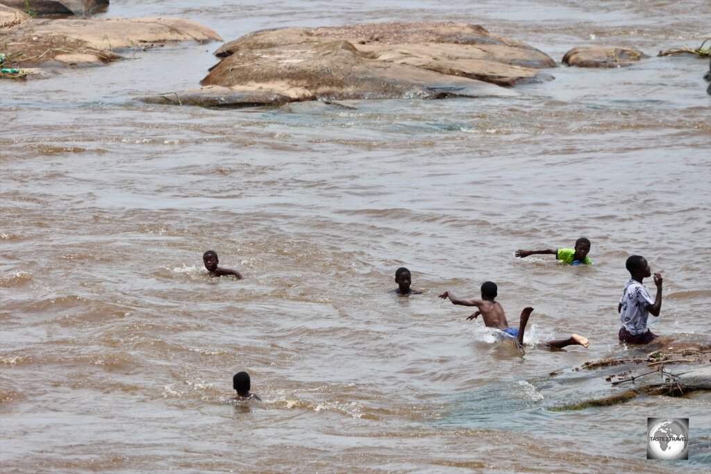 As seen from the terrace of Les Rapides, young dare-devil kids swim in the turbulent waters of the raging Congo River.
