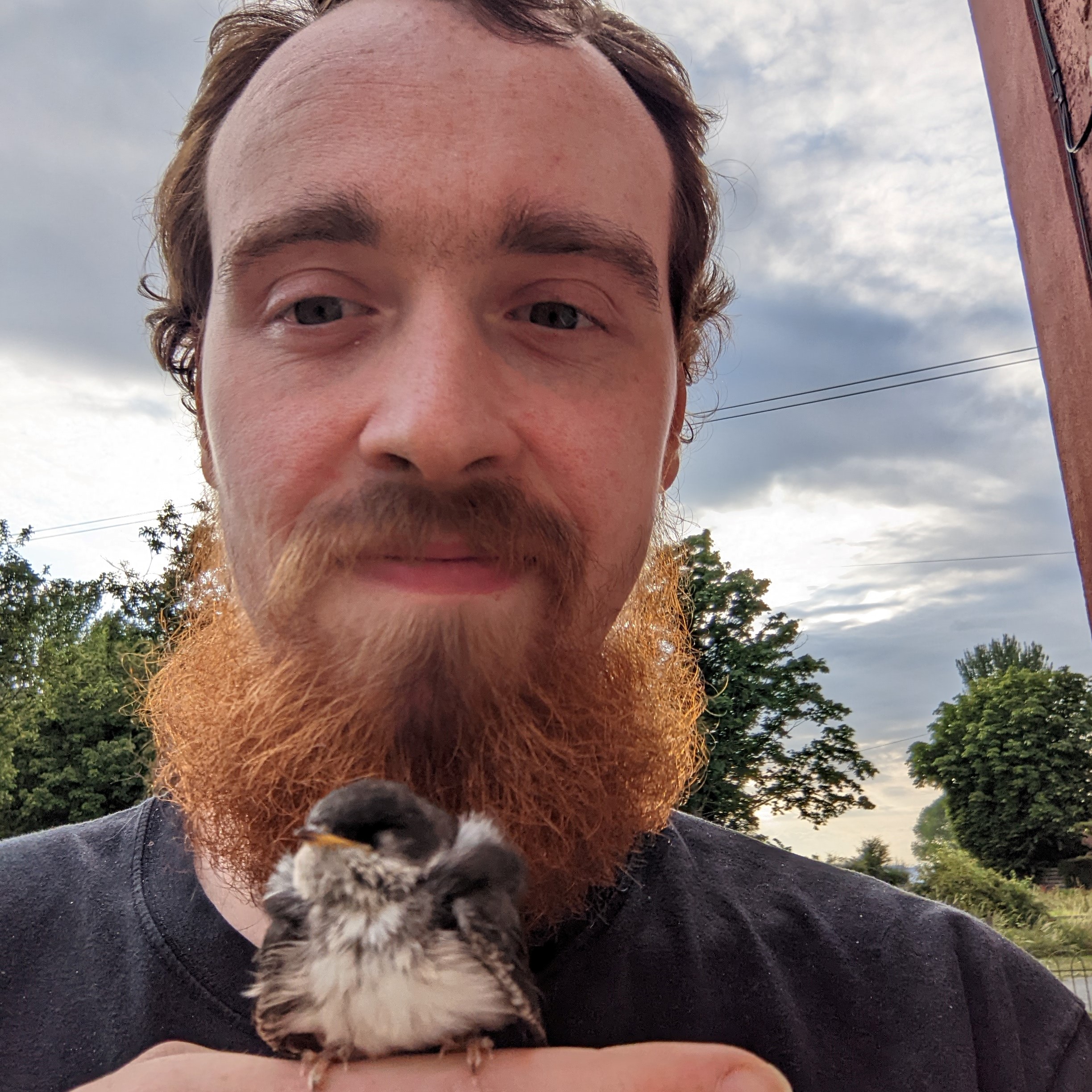 Christian Guyton, smiling while a small bird perches on his finger.