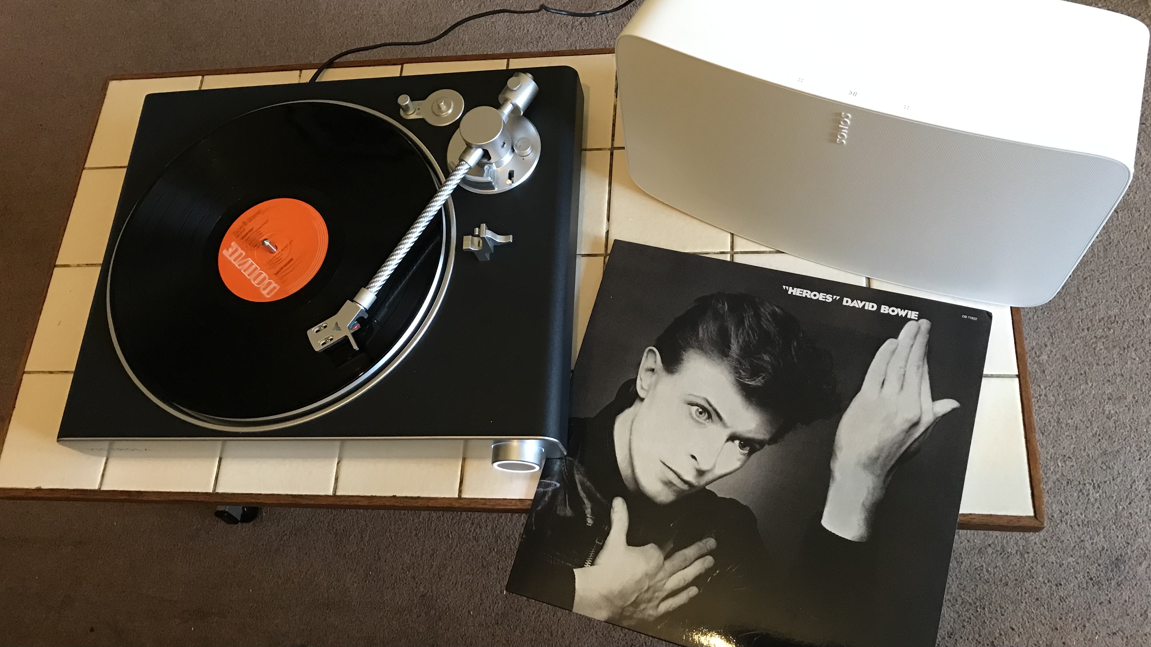 Victrola Stream Carbon and vinyl, on a beige coffee table