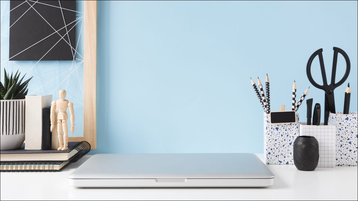 A closed laptop on a desk surrounded by minimalist decor and accessories.