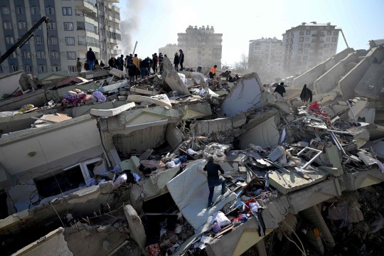 TOPSHOT - Families of victims stand as rescue officials search among the rubble of collapsed buildings in Kahramanmaras, on February 9, 2023, three days after a 7,8-magnitude earthquake struck southeast Turkey. - The death toll from a huge earthquake that hit Turkey and Syria climbed to more than 17,100 on on February 9, as hopes faded of finding survivors stuck under rubble in freezing weather. (Photo by OZAN KOSE / AFP) (Photo by OZAN KOSE/AFP via Getty Images)