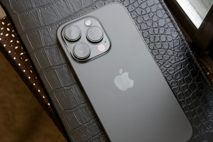 A black iPhone 14 Pro laying face-down on a black journal.