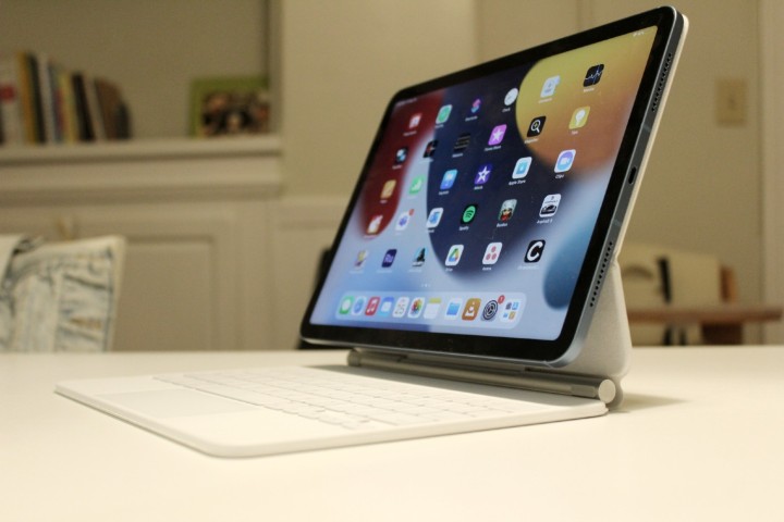 Someone holding an iPad Air against a wooden floor.