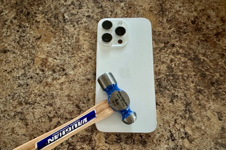 And iPhone 15 Pro Max in white with a hammer head sitting on top.